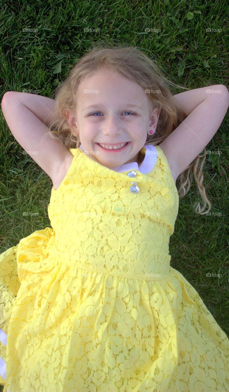 Little girl resting on green grass