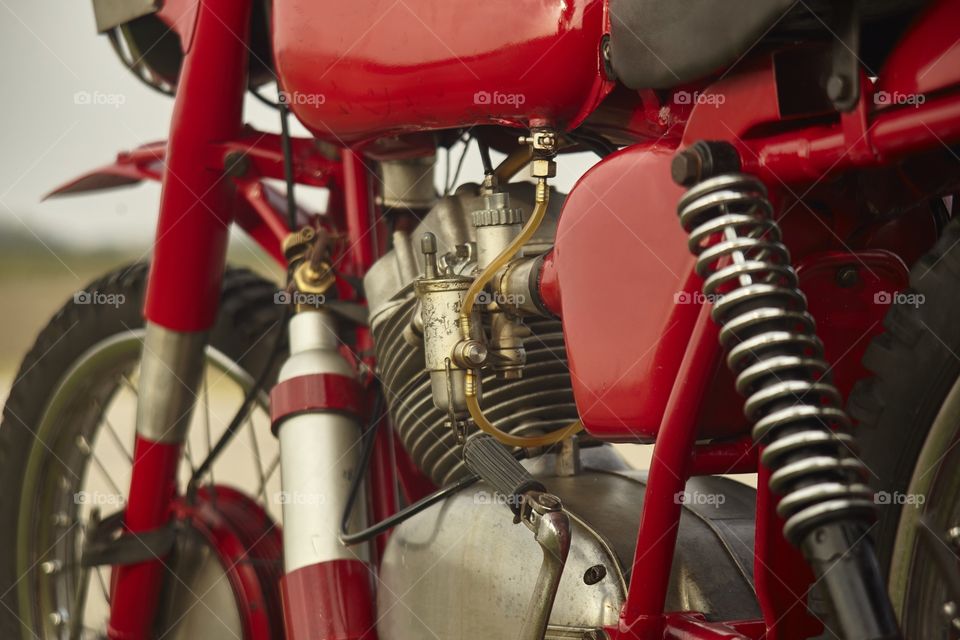 Engine of a very old vintage motorcycle with visible details of the suspension, the carburetor and various other mechanical parts.