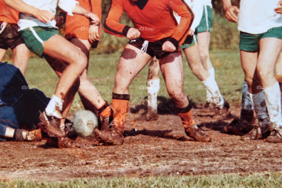 Old photo of legs of men playing soccer in the mud