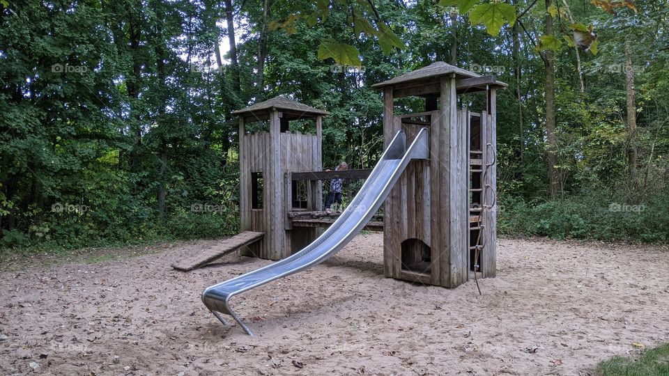 playground with towers and a slide. Sandy surface.