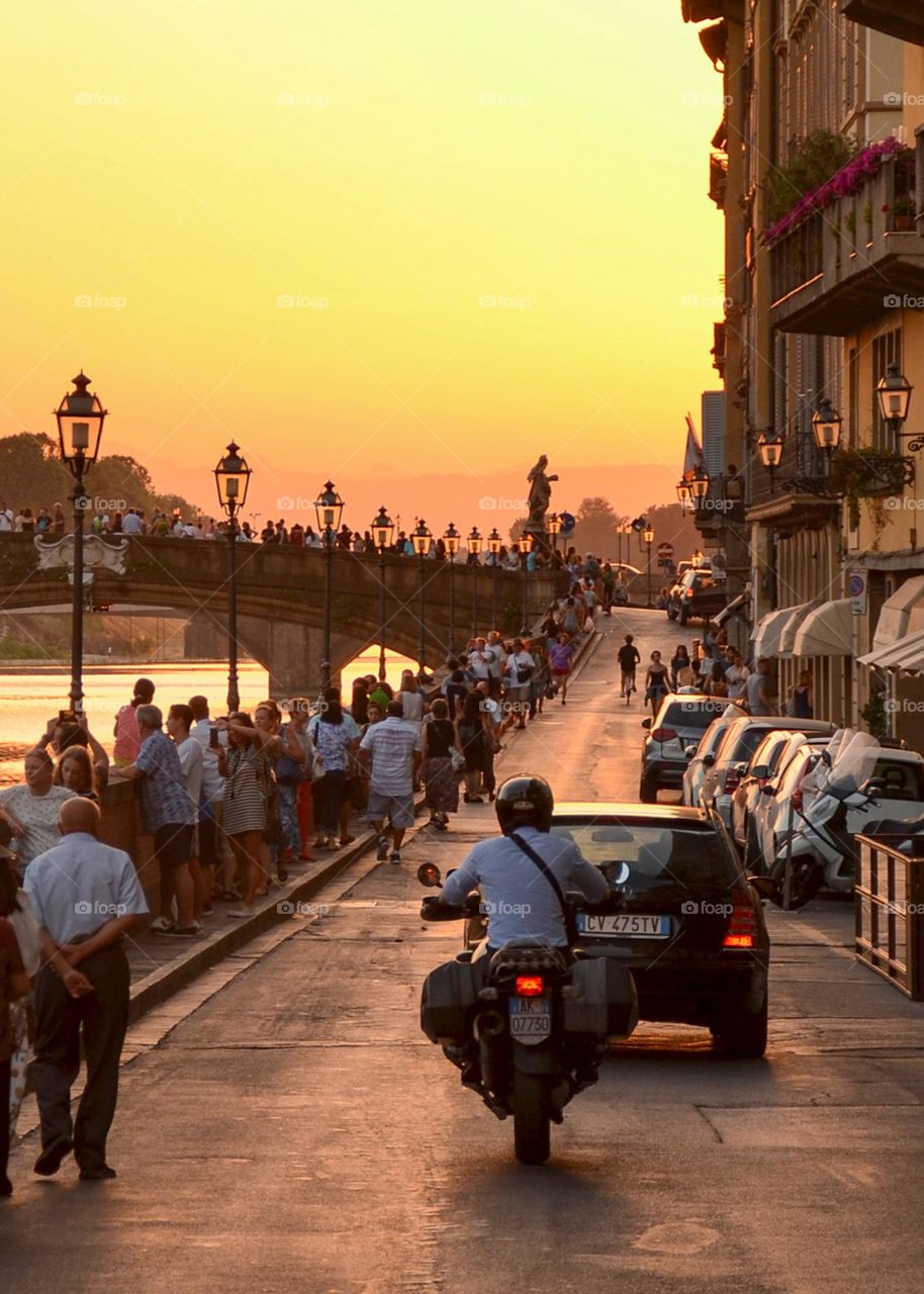 A Man in Casual Business Clothes Rides Motorcycle on City Road. Summer evening , Florence