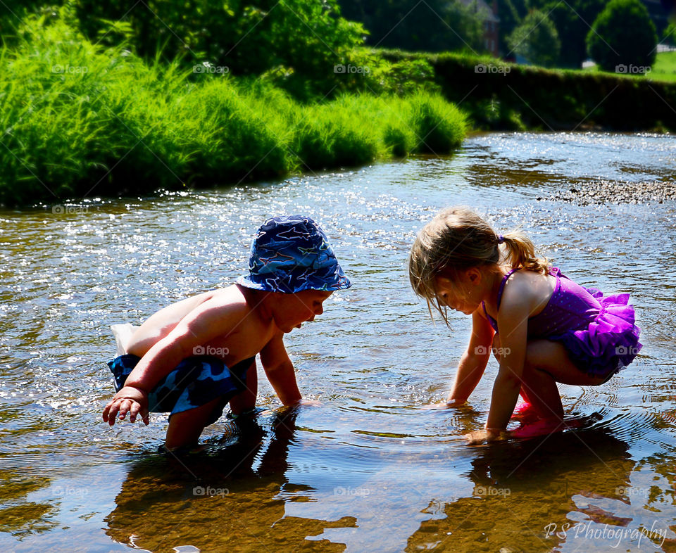 siblings playing in creek