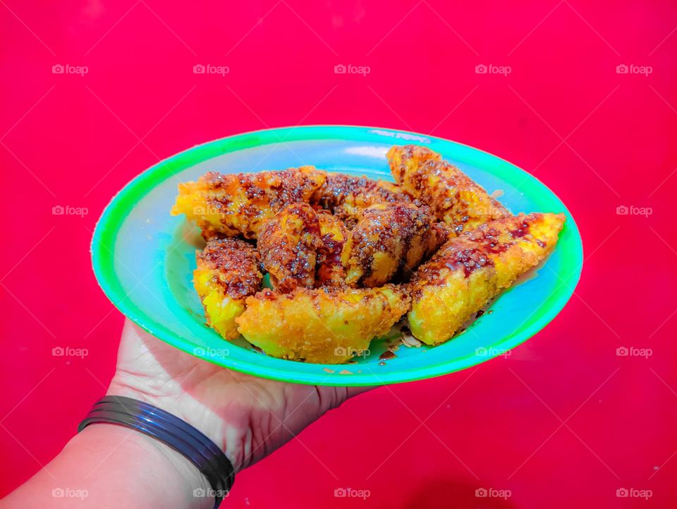 I'm holding a plate that contains crispy fried bananas covered with chocolate milk