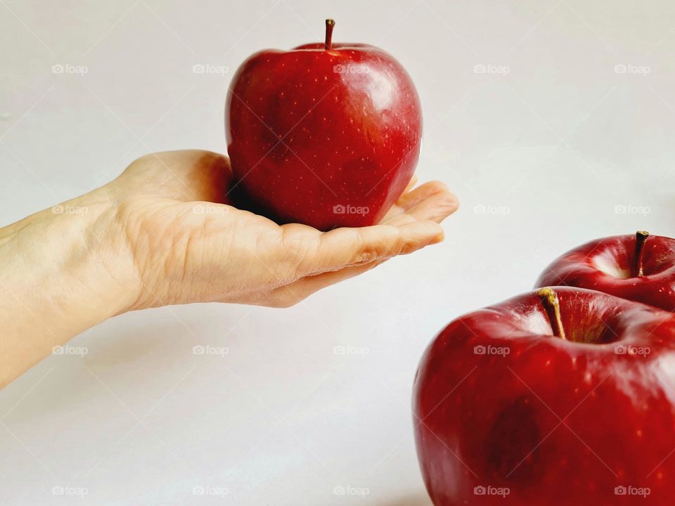 hand holds a delicious red apple