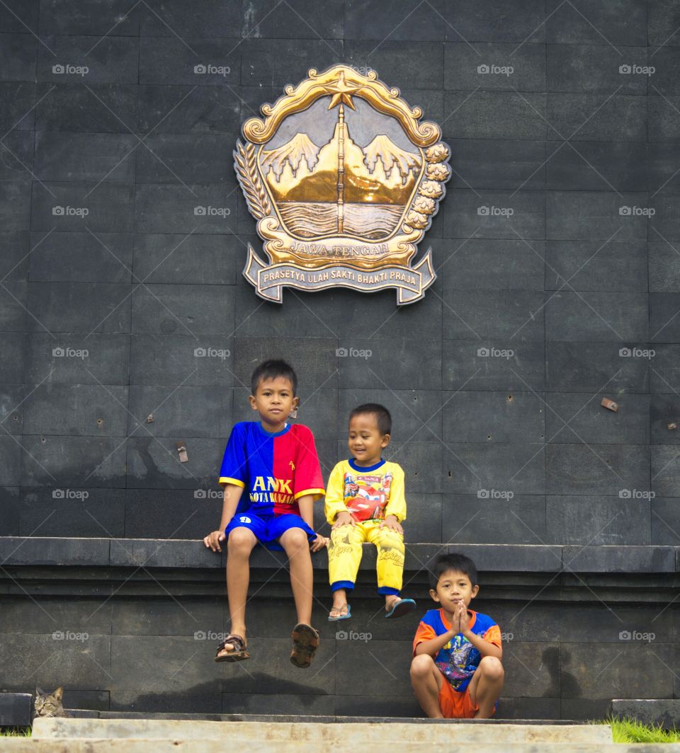 Children sitting in front of symbol on wall