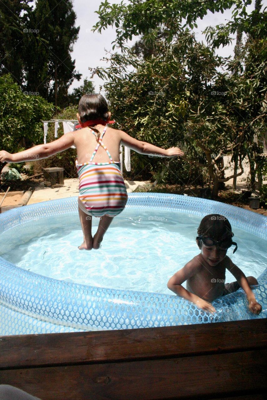 Girl jumping into little swimming pool 