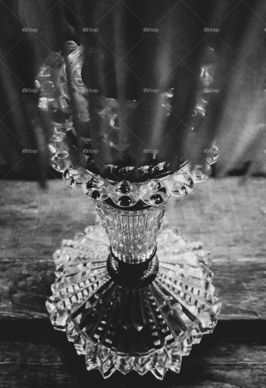 Black and white photograph of an antique glass lamp. Looking through the fringe on the lamp shade.