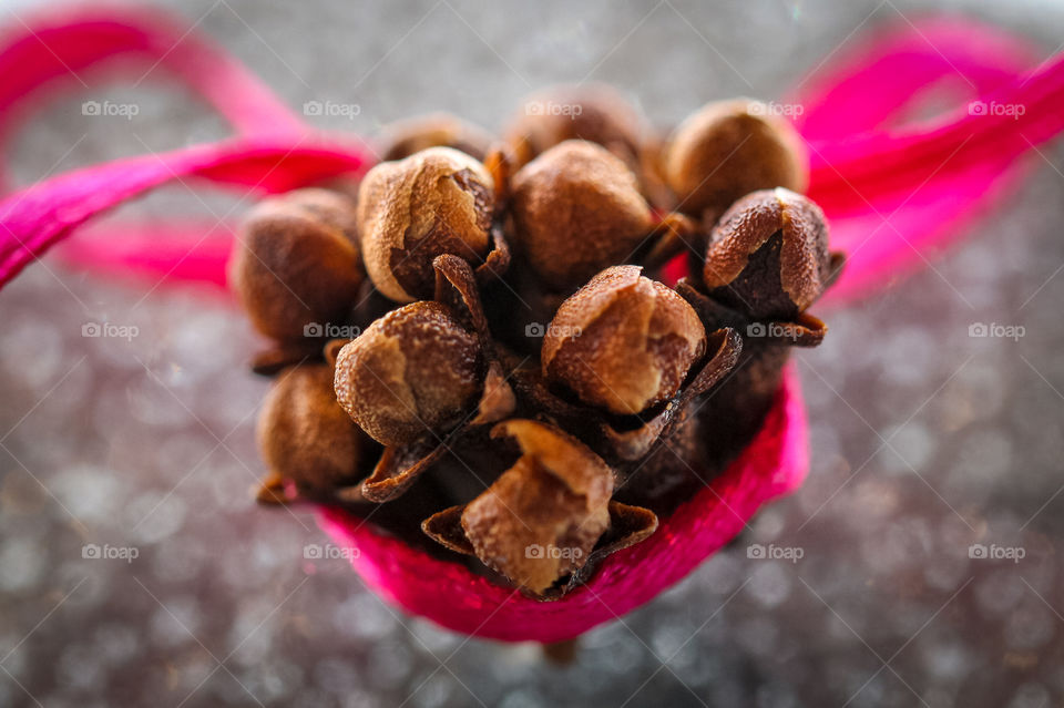 Macro shot of a bouquet of clove buds wrapped in a pink ribbon. Cloves are the aromatic, dried, unopened flower buds of Syzygium aromaticum, an evergreen tree in the myrtle family. They come from Madagascar, Indonesia & Sri Lanka. 