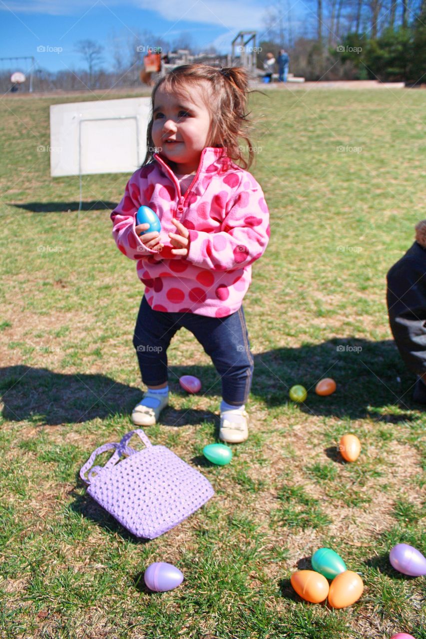 Adorable little girl having fun with easter eggs at park