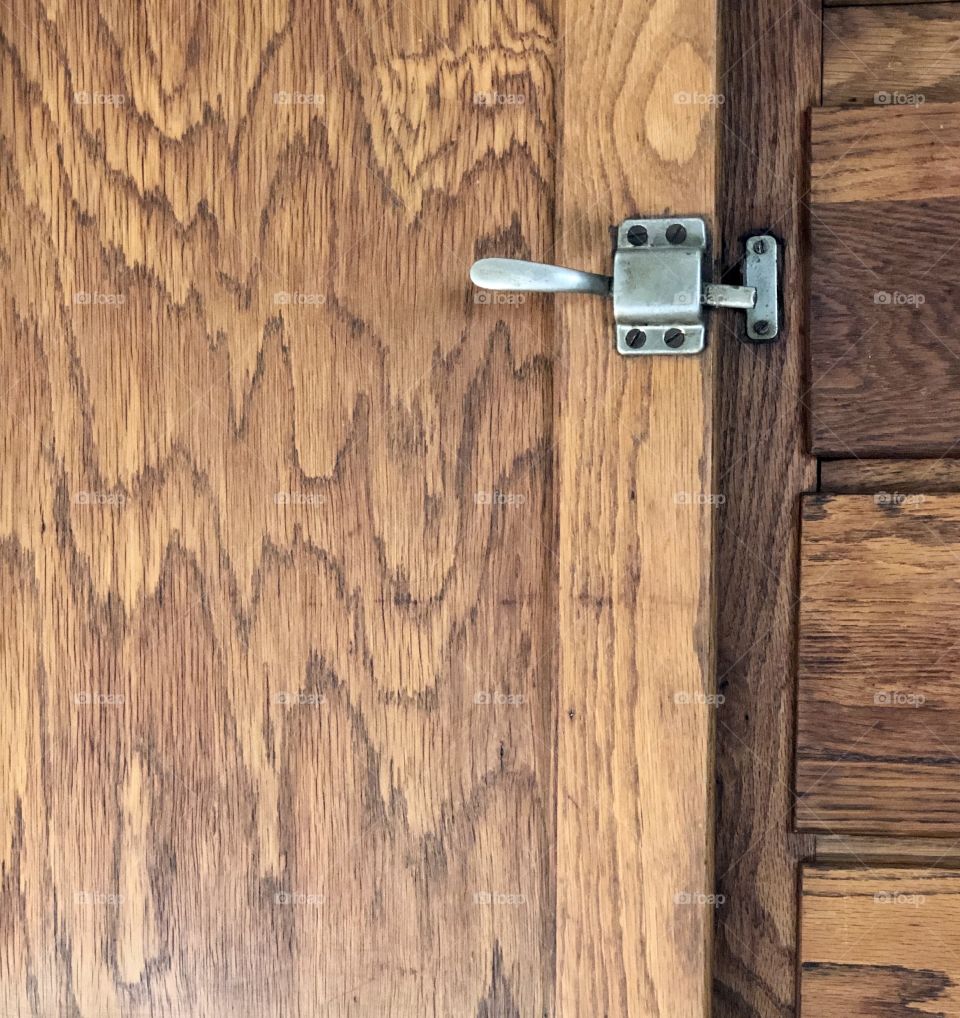 Full frame closeup of antique wooden wardrobe with drawers and door with metal latch 