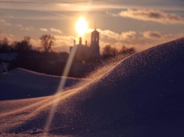 a snow whirlwind picks up sparkling snowflakes in the rays of the setting sun