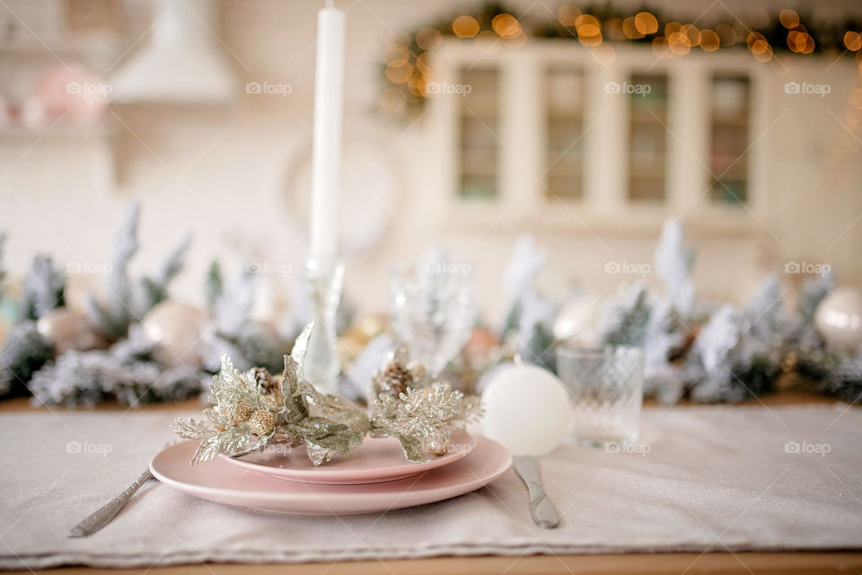 Festive winter cozy kitchen interior with garlands, decorations and gifts.  Christmas dinner at the decorated table.