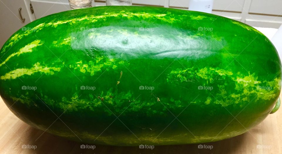 A huge  green watermelon sitting on kitchen Island.