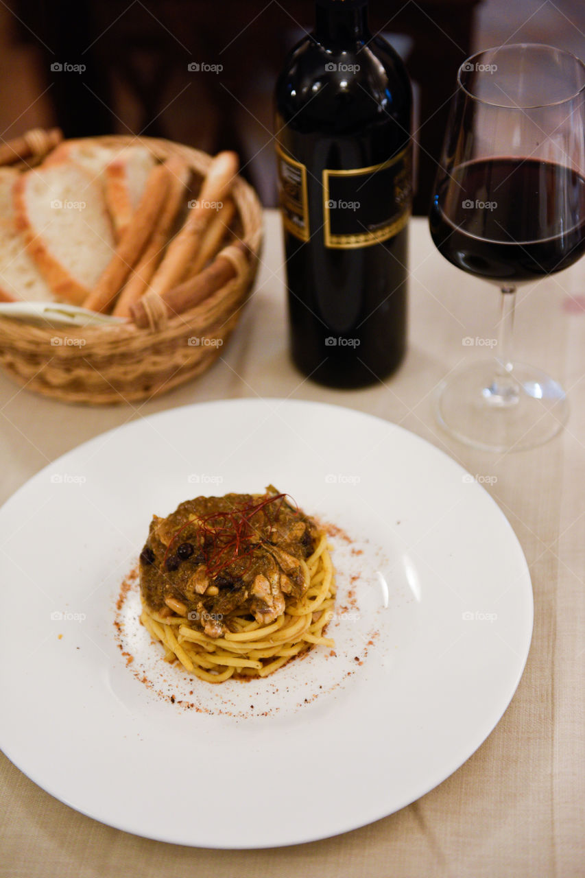 Pasta dish at the restaurant in Sicily with red wine and bread.