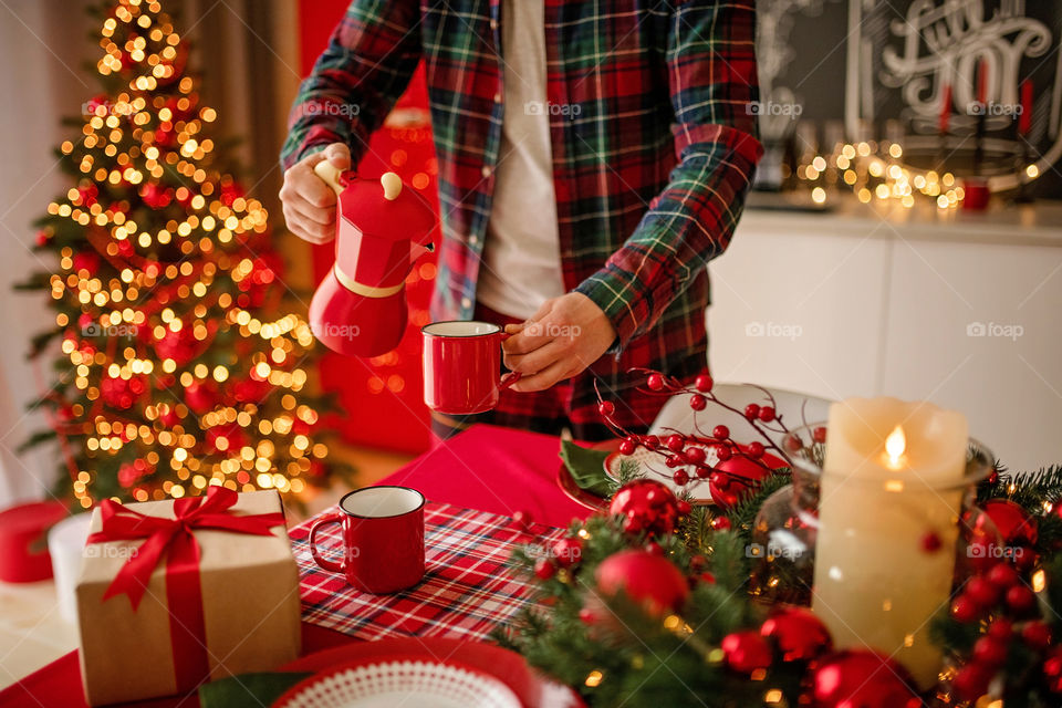 Festive winter cozy kitchen interior with garlands, decorations and gifts.  Christmas dinner at the decorated table.