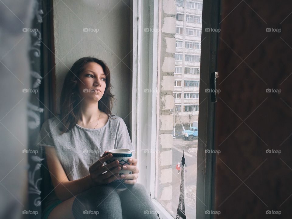 Woman sitting in window with cup of coffee