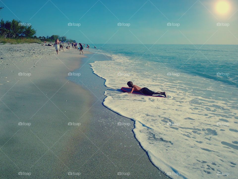 Young boy on his boogie board on a beautiful sunny day at the beach.