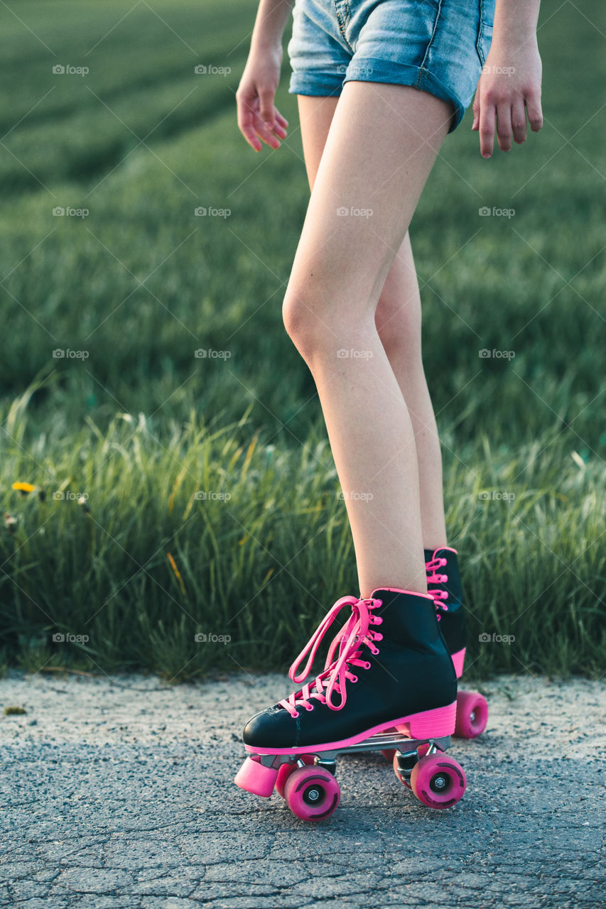 Teenage smiling happy girls having fun rollerskating, jumping, spending time together on summer day. Teenage smiling happy girls having fun walking outdoors, hanging, spending time together on summer day. Real people, authentic situations