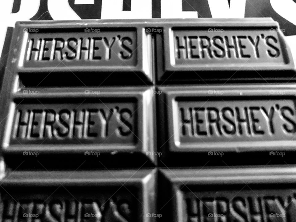 Hersey’s chocolate pips shot in black and white sitting on to of candy bar wrapper. 