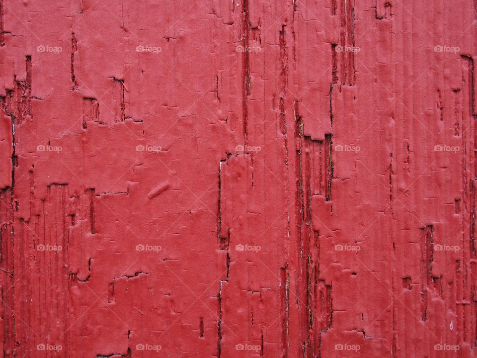 Rich and detailed texture on an old an worn wall that has been painted bright red. 