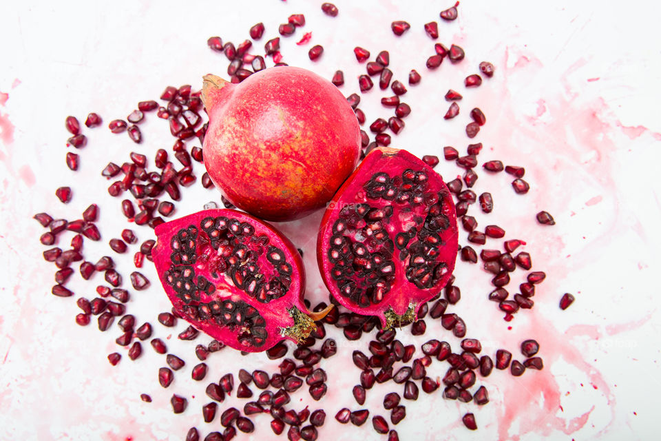 Fresh juicy summer fruits. Whole, cut and pieces of fresh pomegranates. Love this red fruit for summer days! Close up on a white background. Pomegranate juice.