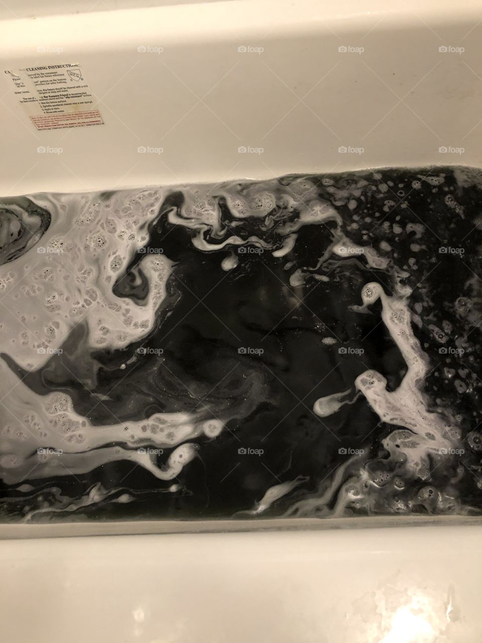 A glittery bath bomb in the bath, with foam and warm water a pristine white bathtub. 