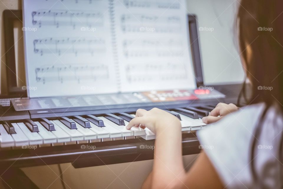 an Asian girl is practicing the piano in her room