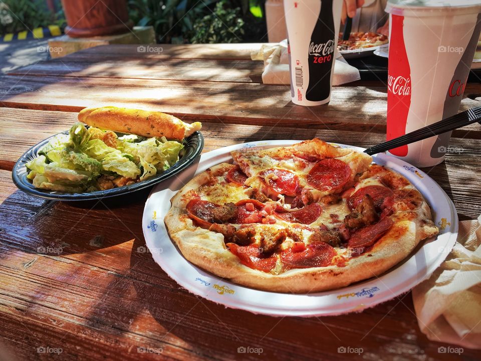 Pizza and a Salad on a Picnic Table Outside 