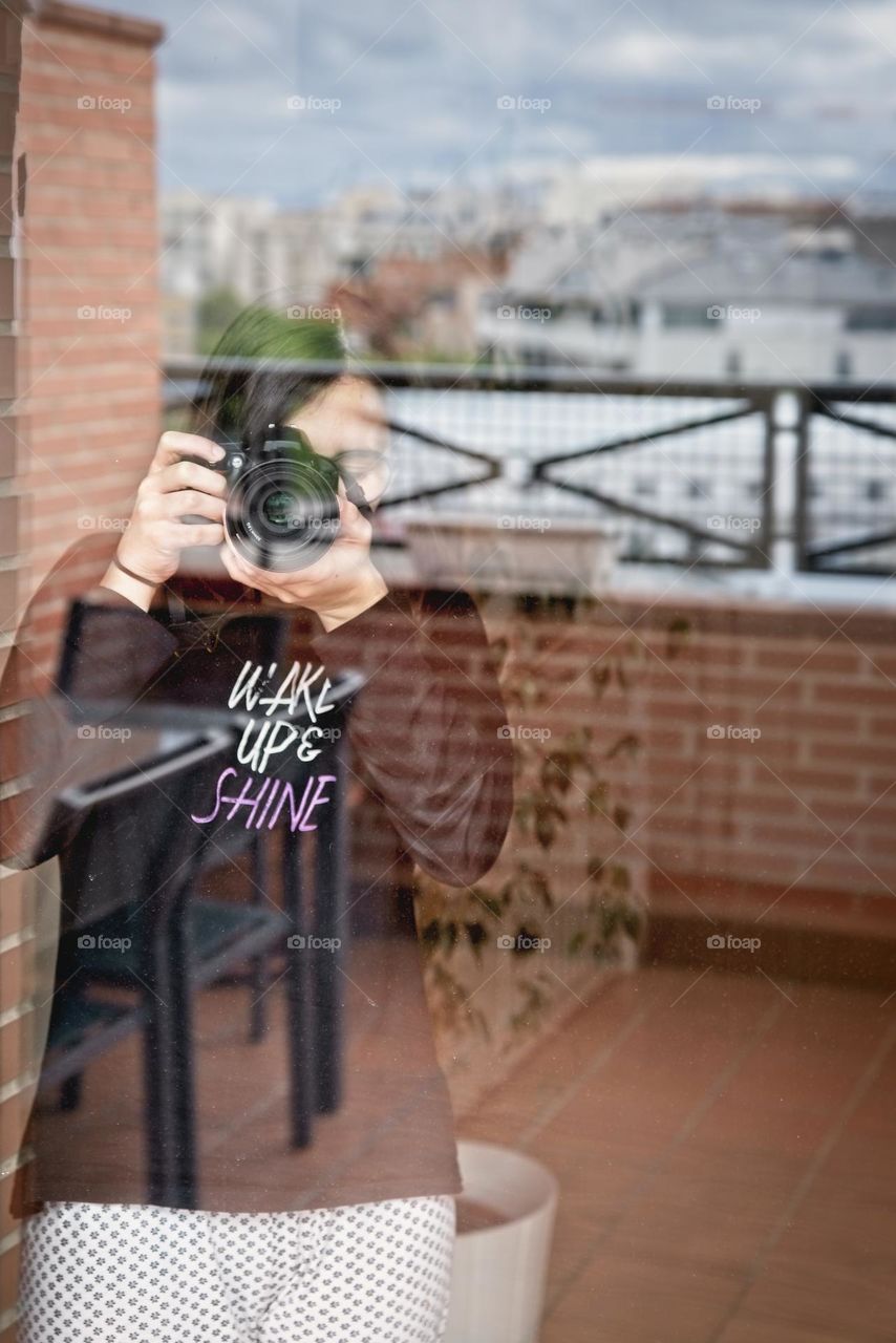 A young woman takes pictures through the window