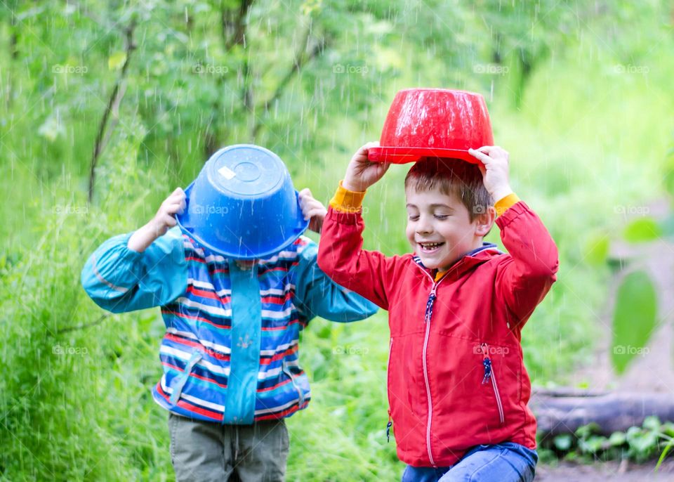 Children Playing in Rainy Spring Day with Buckets on Their Heads