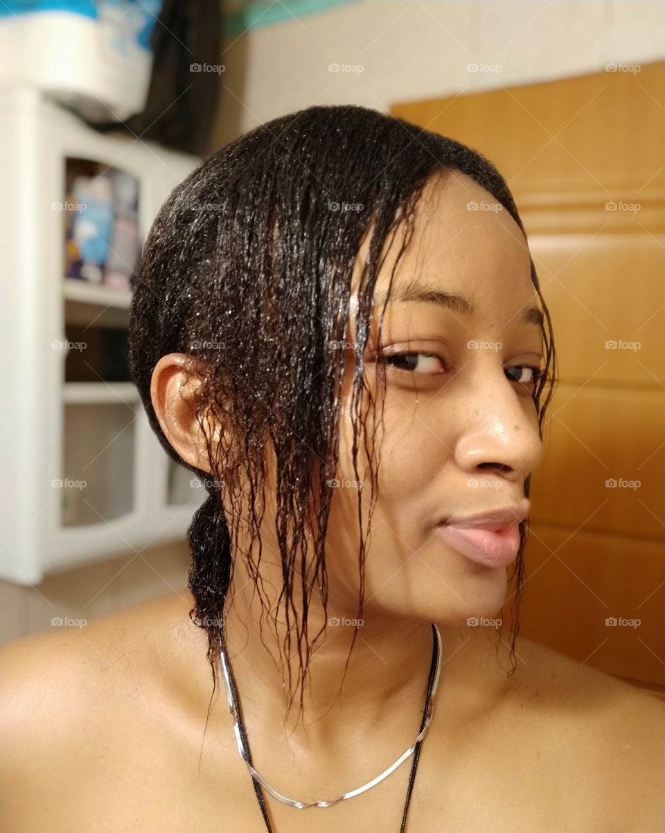 Side view of a similing girl's face with a short black wet hair