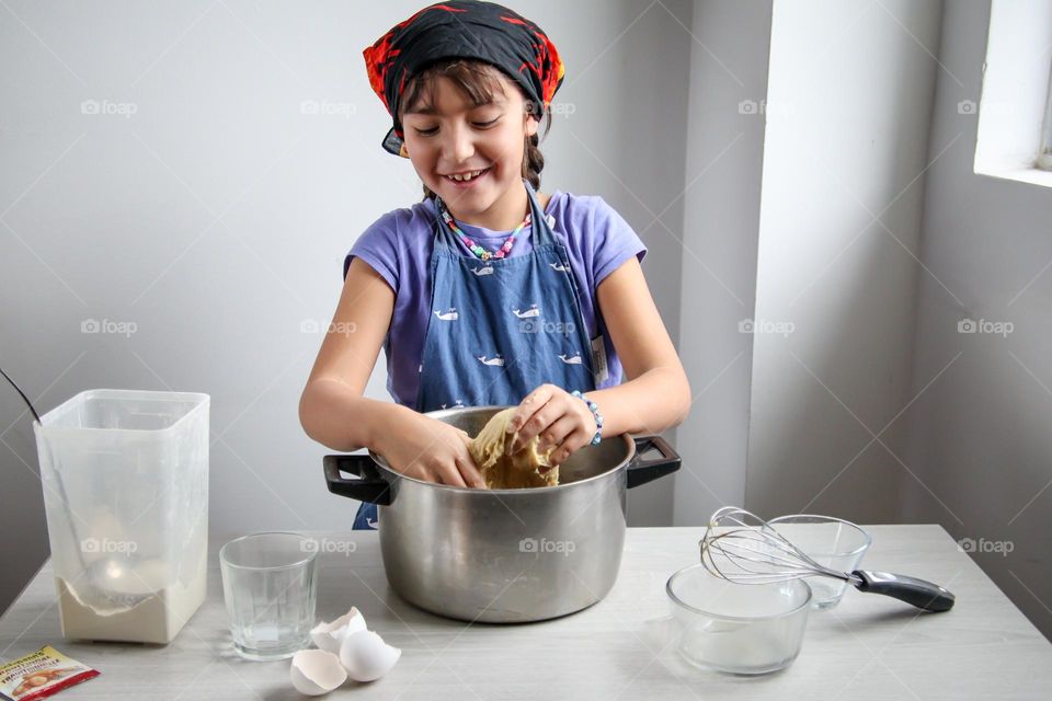 Cute girl is mixing a bread dough