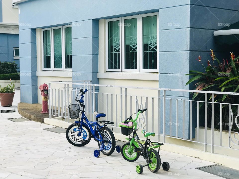 A blue and green bicycle’s stand near the blue and white combination wall 