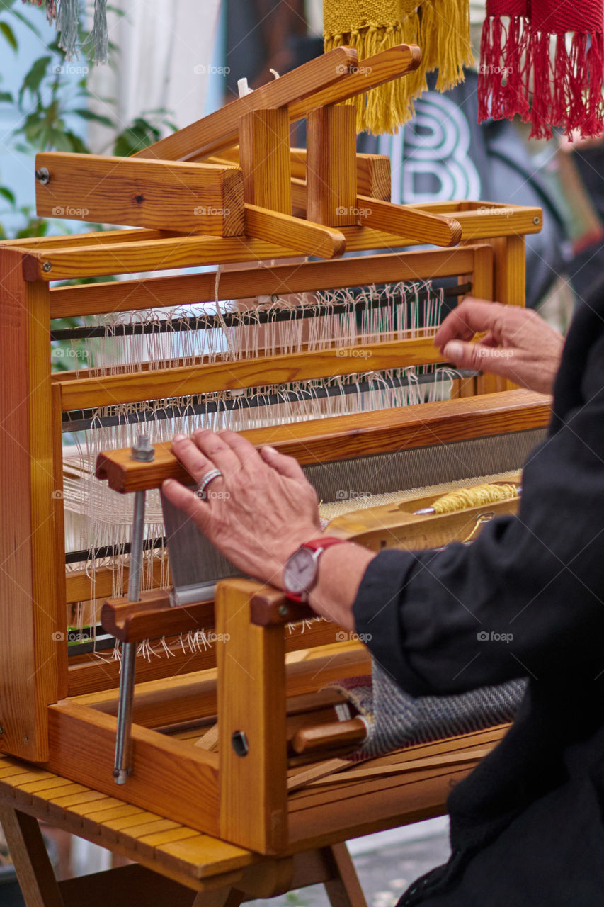 Mujer manejando la reproducción de un telar antiguo. 