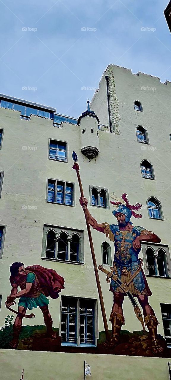 The “Goliath House” in the German city of “Regensburg” features the biblical confrontation between “David” and the giant Philistine “Goliath”. “David’s” victory over him makes him king of the land. 2023. Hypnotic Productions
