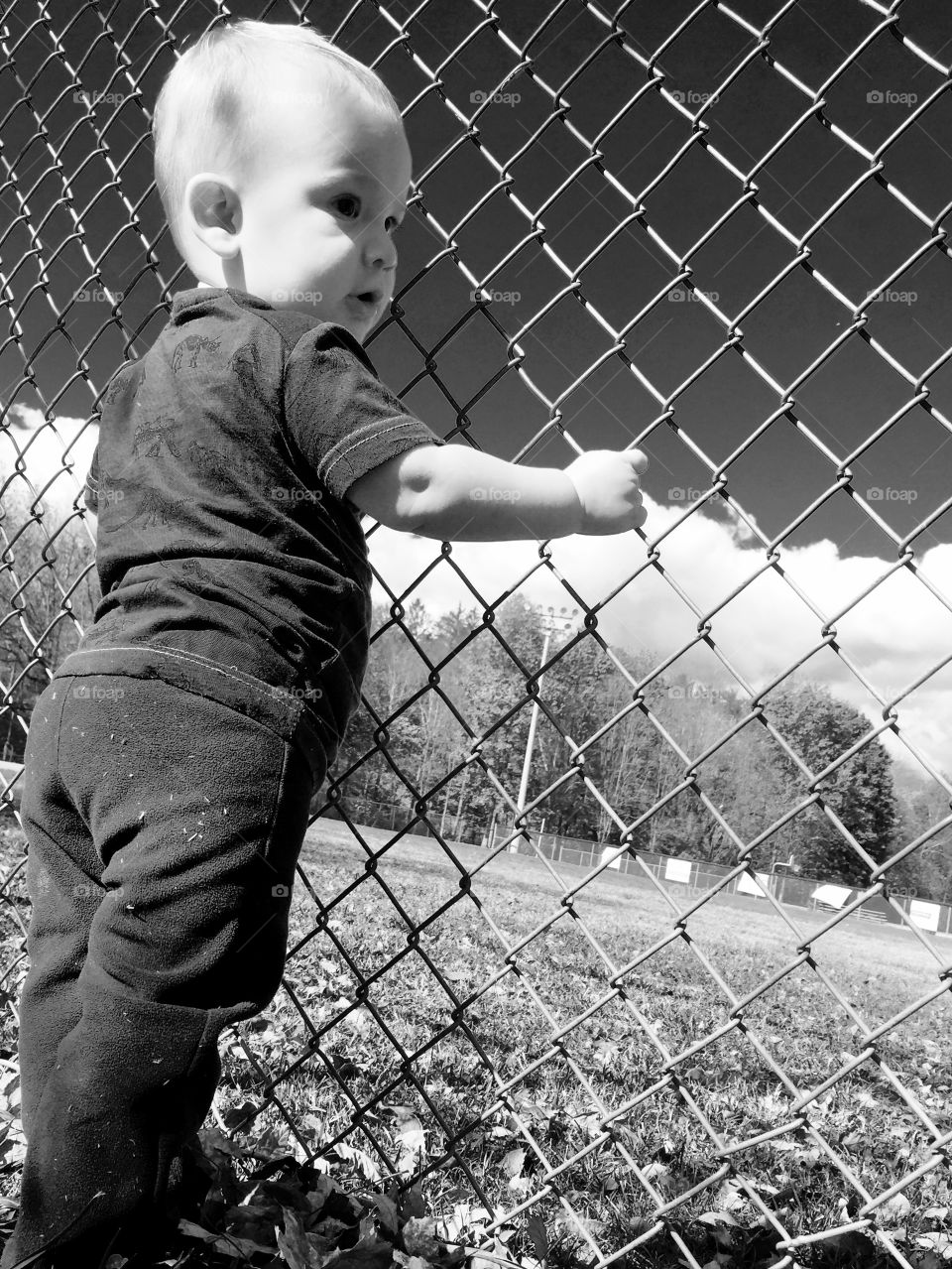 Toddler boy standing near mesh wire fence