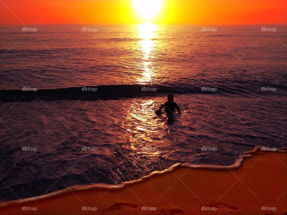 Small boy enjoying an ocean sunset.