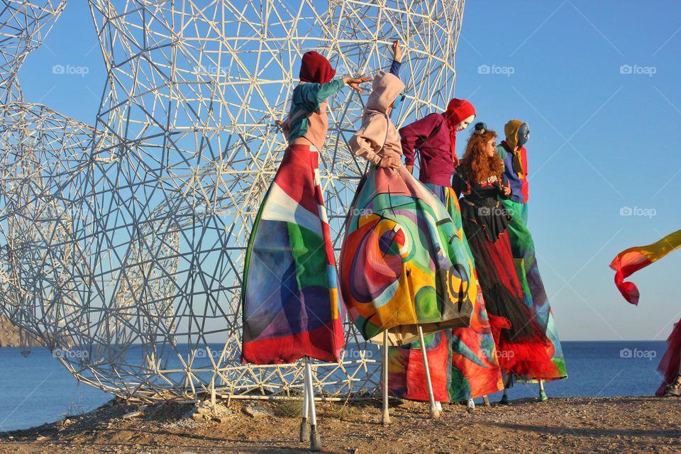 People in colored carnival clothes against the background of the sky and a metal structure