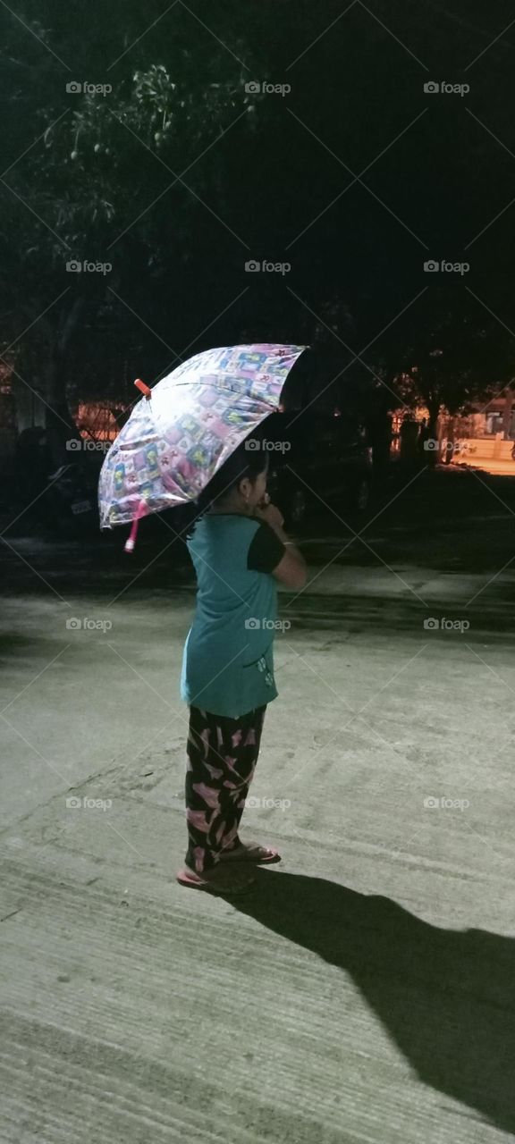 A girl is standing front of her home at night 🌃🌉 in rain. she takes umbrella because saving herself from rain ☔