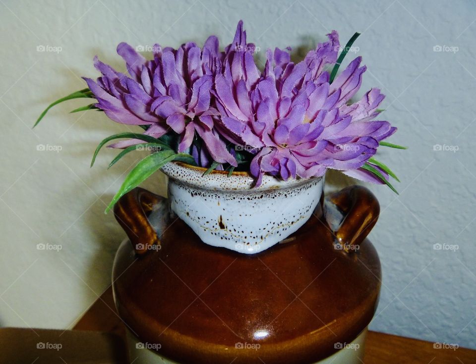 Fake light purple flowers in brown vase