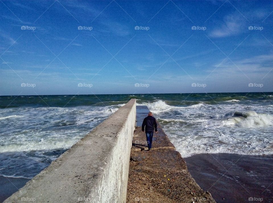 a man walks by pier человек идёт по пирсу
