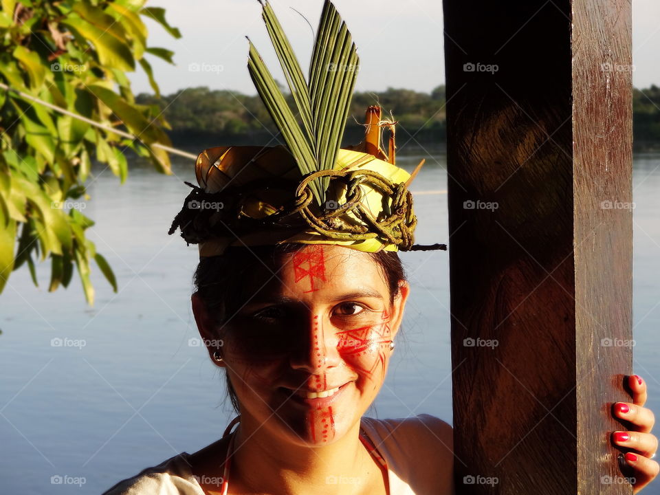 Amazon rainforest woman with native face paint and crown. Amazon river near Iquitos Peru.