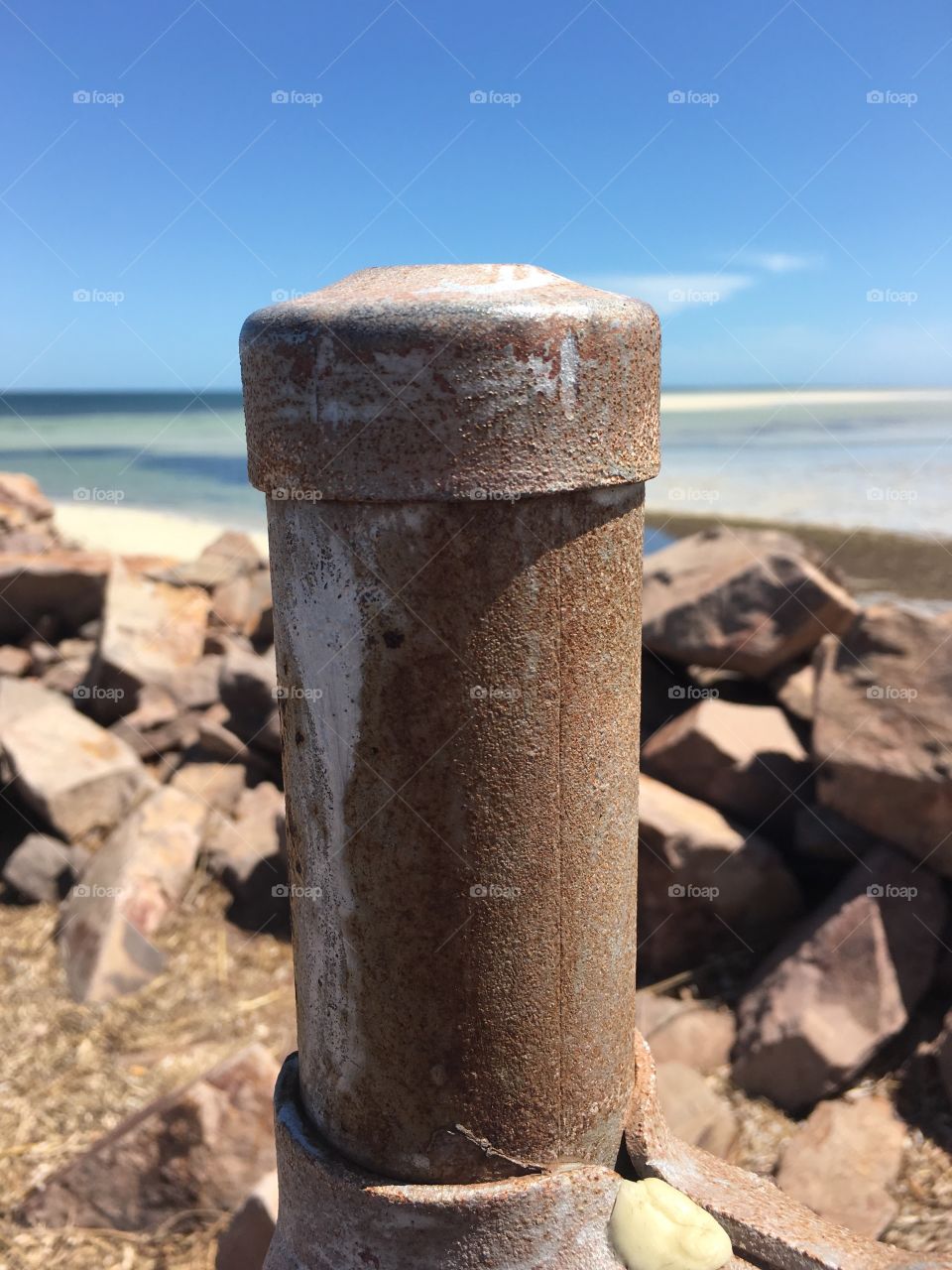 Rusty metal post on Jetty with view of ocean background 