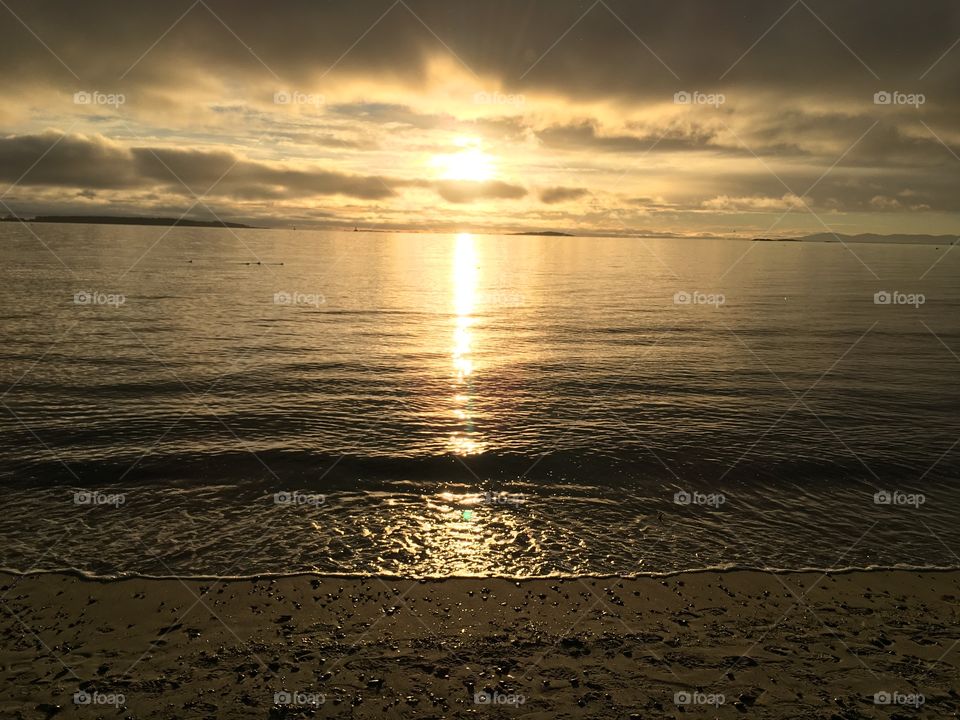 Sun shining over the ocean illuminating the sand