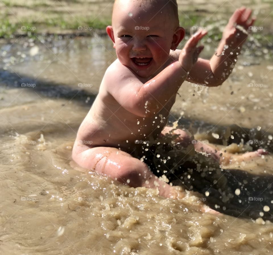 Baby playing & splashing in mud puddle 