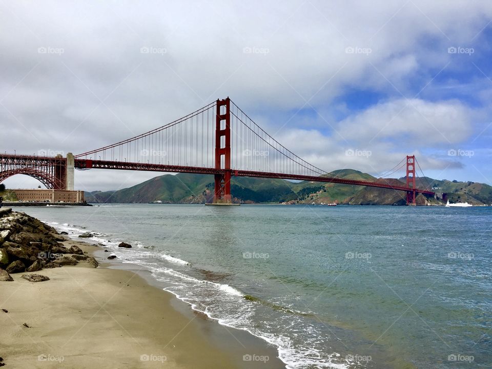 The Golden Gate Bridge from a beach with gently crashing waves 