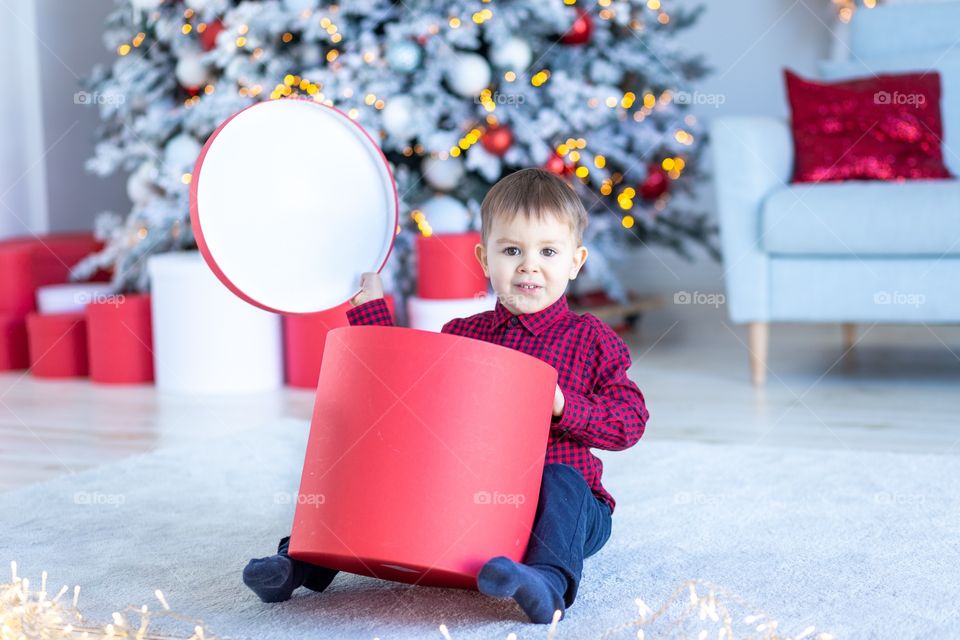 boy and gift box next to christmas tree