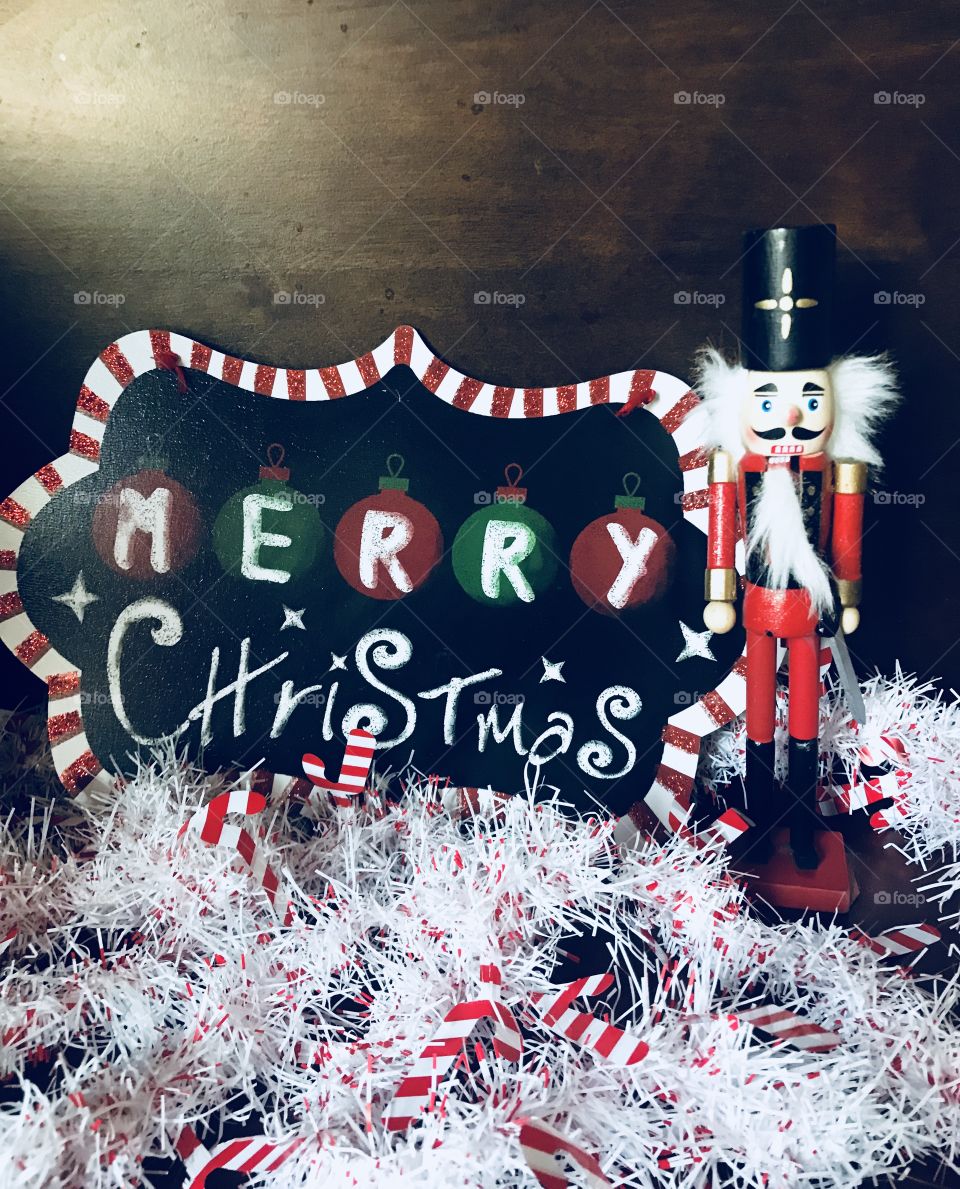 A beautiful colorful green, black, red, white merry Christmas sign with a nutcracker standing by 