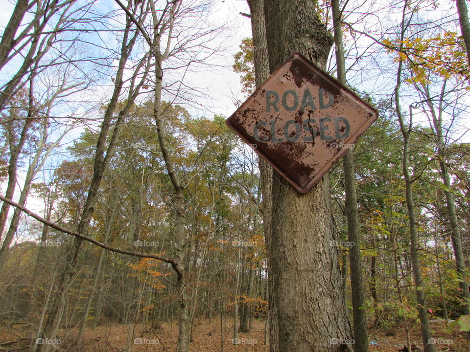 Creepy rusted road closed sign in the middle of the woods