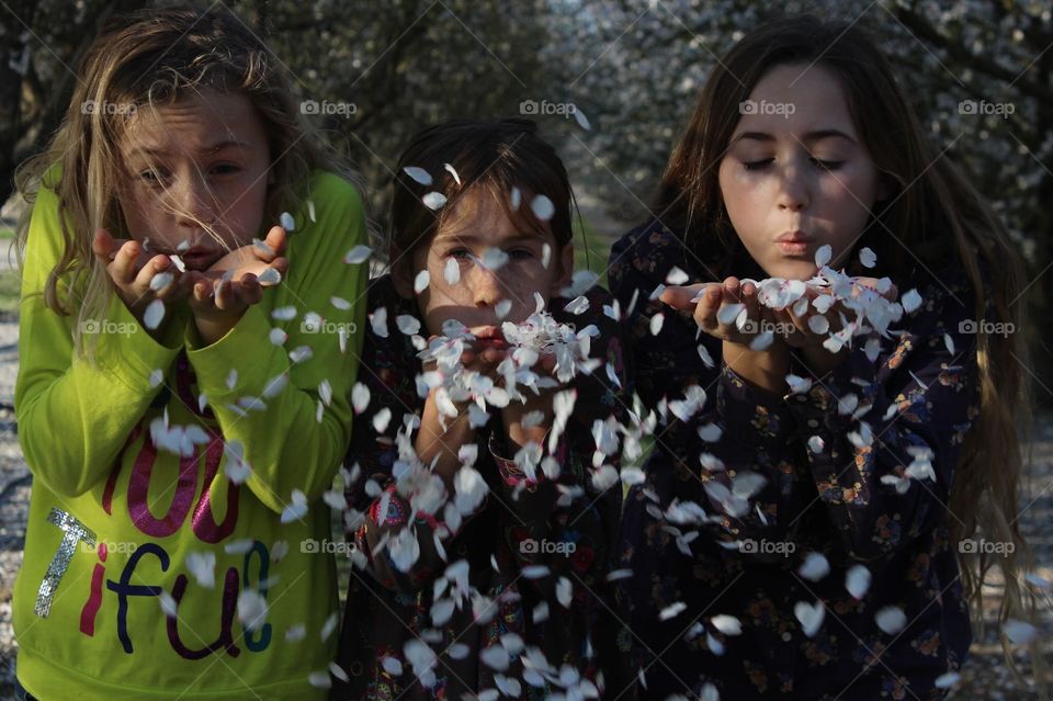 girls blowing almond petals